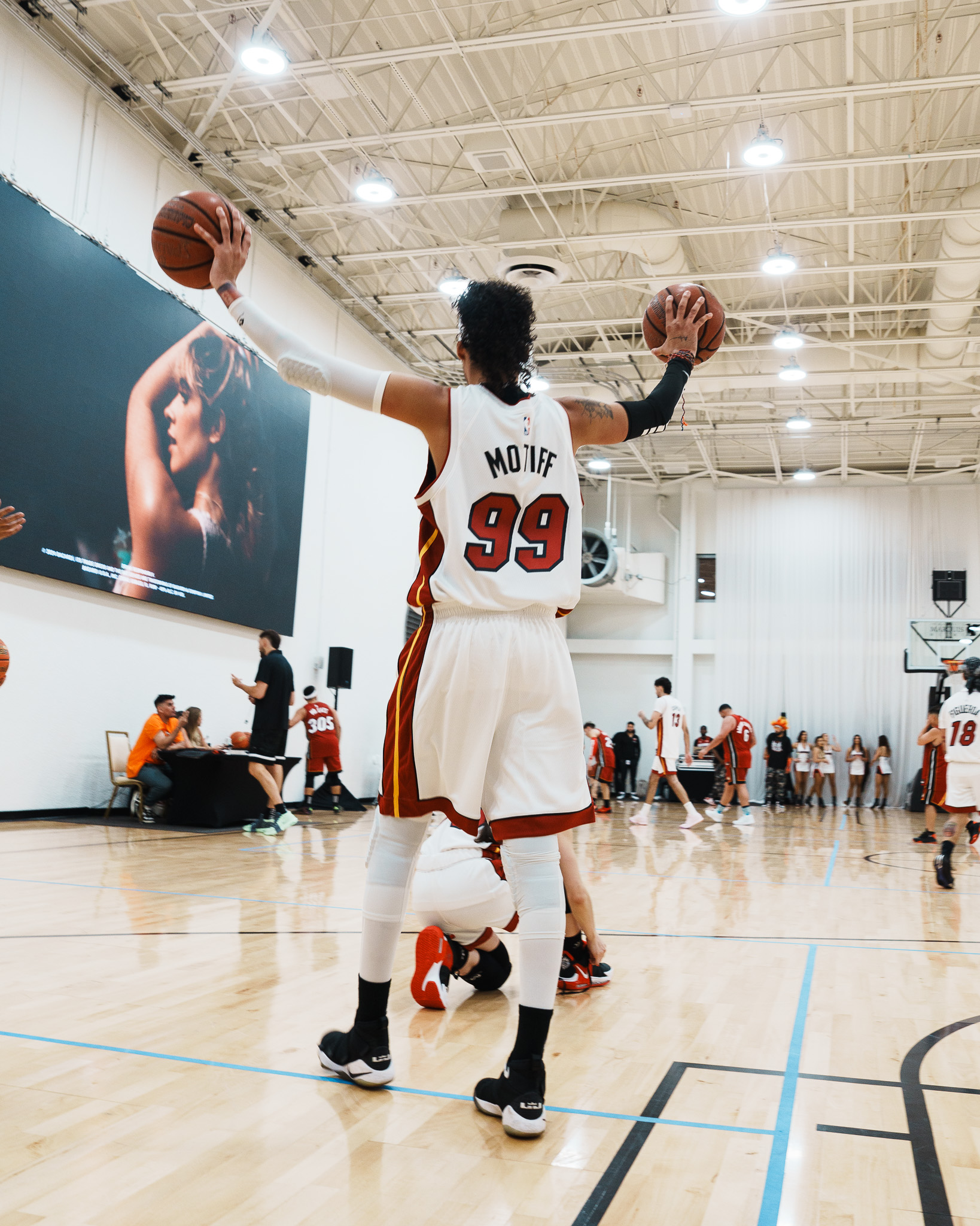 Player celebrating on court with two basketballs at the Sony Music Celebrity Game